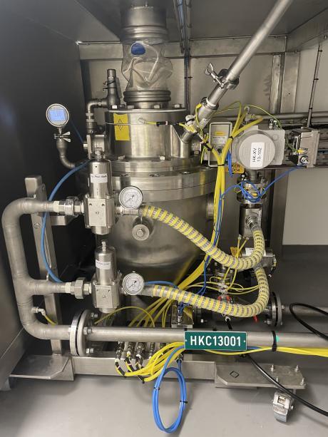 Front view of a stainless steel pneumatic transfer component, with pressure gauges, regulators, and yellow flexible pipes for conveying powders or granules.